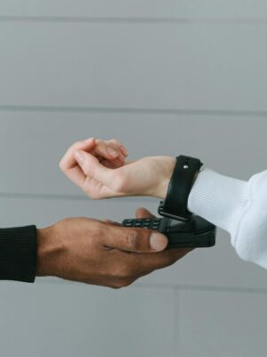 A person using a smartwatch for a secure contactless payment on a portable terminal indoors.
